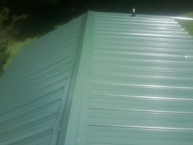 New green metal panels meeting at the ridge of a roof — Flat Roof Repair work by our crew in Emigrant
