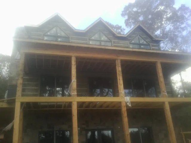Dormers and porch framing on a large log home under construction — Roof Coating work by our crew in Emigrant