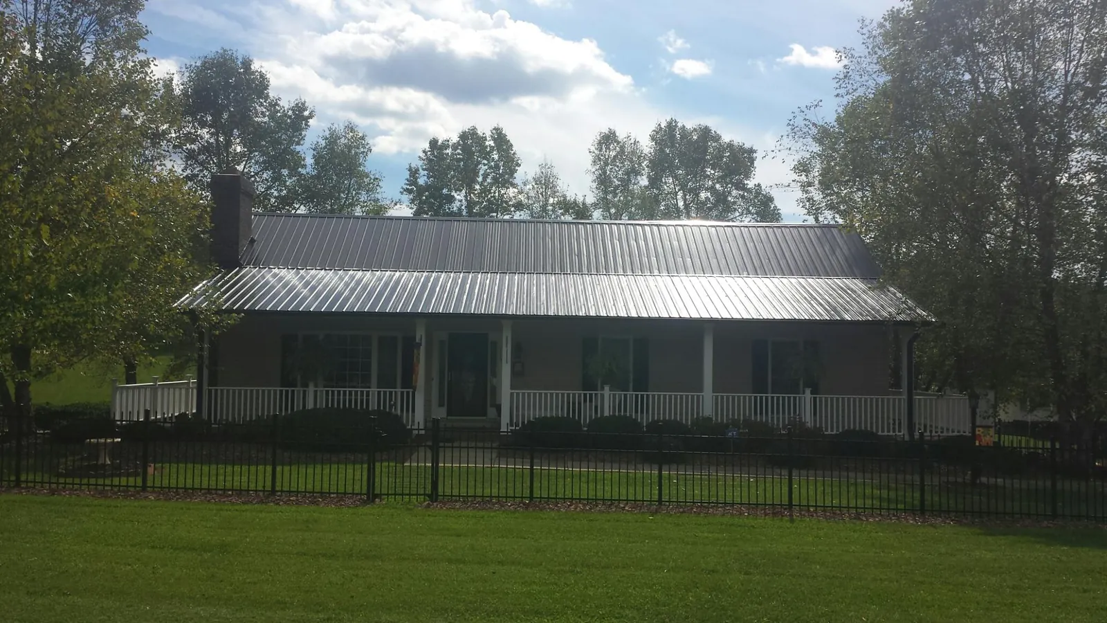 Gray metal roof on a brick ranch with a full width front porch — Gutter Guard Installation work by our crew in Emigrant