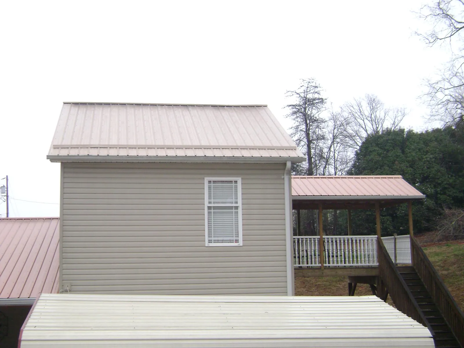 Tan metal roofs on a two story addition and attached porch, from a Roof Replacement job in Emigrant