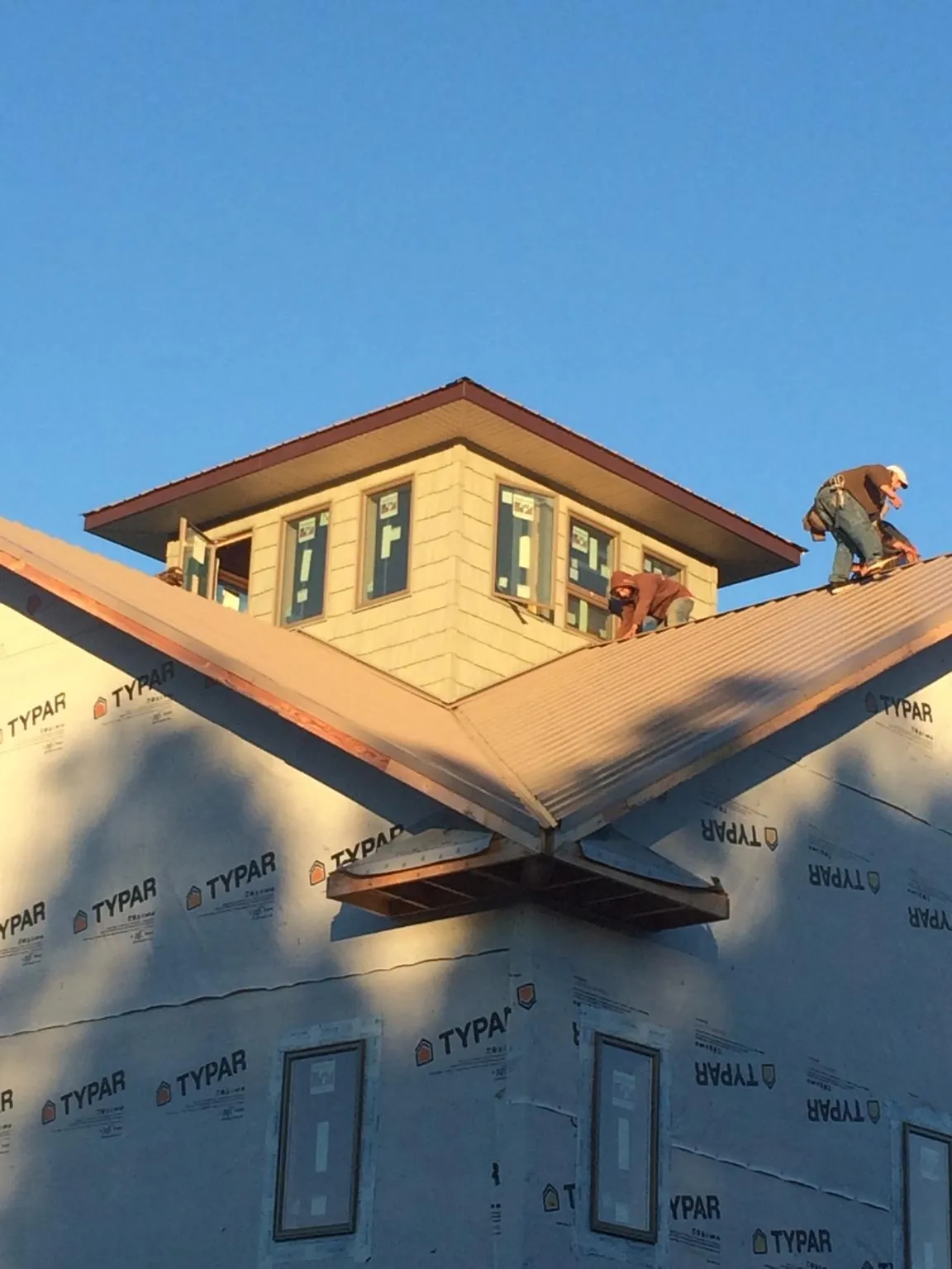Roofers working around a rooftop cupola on a new metal roof at sunset — Roof Waterproofing in Emigrant by Roofing Brothers